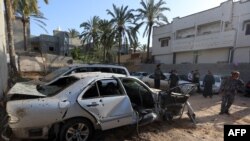 FILE - Libyans check the site of shelling north of the Libyan capital, Tripoli, April 17, 2020.