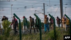 Migrants who successfully crossed the Eurotunnel terminal walk on the side of the railroad as they try to reach a shuttle to Great Britain, July 28, 2015 in Frethun, northern France.