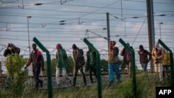 Des migrants qui ont réussi à traverser le terminal d'Eurotunnel marchent sur le côté de la voie ferrée alors qu'ils tentent de rejoindre une navette vers la Grande-Bretagne, le 28 juillet 2015 à Frethun, dans le nord de la France. (Photo AFP/Philippe Huguen)