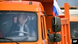 Russian President Vladimir Putin drives a truck to officially open the much-anticipated bridge linking Russia and the Crimean peninsula, during the opening ceremony near in Kerch, Crimea, Tuesday, May 15, 2018. (Alexander Nemenov/Pool Photo via AP)