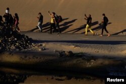 Asylum-seeking migrants, mostly from Venezuela, make videos of themselves and celebrate after crossing the Rio Grande to El Paso, Texas, U.S., as seen from Ciudad Juarez, Mexico, September 19, 2022. (REUTERS/Paul Ratje)
