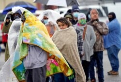 FILE - People wait in line to fill propane tanks in Houston, Texas, Feb. 17, 2021. Millions in the state had no power after a historic snowfall and freezing temperatures created a surge of demand for electricity the power grid could not provide.