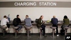 FILE - Show attendees charge their phones at the charging station at CES International Thursday, Jan. 5, 2017, in Las Vegas. (AP Photo/Jae C. Hong)