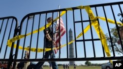 FILE - Pedestrians walk past a barricade preventing them from entering the World War II Memorial in Washington, D.C., Oct. 2, 2013, during a government shutdown. President Donald Trump has threatened a government shutdown to secure funding for a wall along the U.S.-Mexican border, one of his key promises during the election campaign.