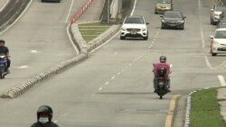 A food delivery rider tries to save time by traveling down a lane in the wrong direction. (VOA/Dave Grunebaum)