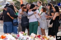 Sebuah kelompok orang bereaksi setelah meletakkan bunga sebagai penghormatan di dekat lokasi kejahatan di Bondi Junction, Sydney, Senin, 15 April 2024. (Foto: AP)