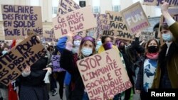 FILE - Women hold placards during a demonstration to call for gender equality and demand an end to violence against women, on International Women's Day in Brussels, Belgium, March 8, 2021. 