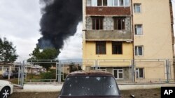 Shrapnel holes in a car as a building burns in the background after shelling by Azerbaijan's artillery during a military conflict in self-proclaimed Republic of Nagorno-Karabakh, Stepanakert, Azerbaijan, Oct. 4, 2020.