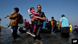 Un réfugié syrien porte son enfant vers les plages de l'île de Lesbos, en Grèce, le 4 octobre 2015.
