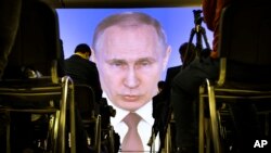 FILE - Journalists watch as Russian President Vladimir Putin gives his annual state of the nation address in Manezh in Moscow, Russia, Thursday, March 1, 2018. (AP Photo/Alexander Zemlianichenko)
