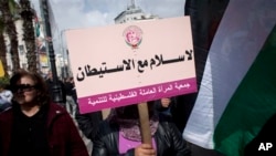 Palestinian protester holds placard with Arabic writing that says "no peace with settlements, the Palestinian Women Labor Association," anti-peace talks rally, Ramallah, March 19, 2014.