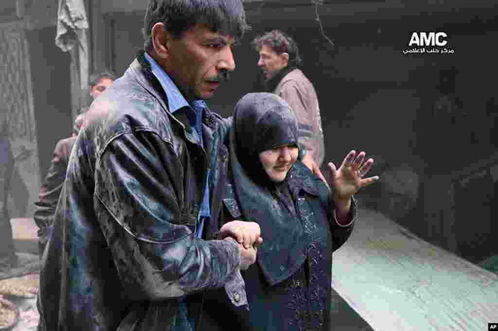 A Syrian man helps a survivor out of a damaged building following an airstrike by Syrian warplanes, Aleppo, April 6, 2014.