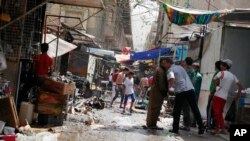 Civilians inspect the site of a bomb attack in Shorja Market in Baghdad, July 17, 2014.