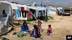 FILE - Syrian women prepare food for their family outside their tents at a Syrian refugee camp in the town of Bar Elias in Lebanon's Bekaa Valley, March 29, 2016. 