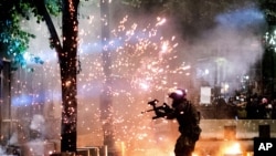 A federal officer fires crowd control munitions at protesters at the Mark O. Hatfield United States Courthouse on July 24, 2020, in Portland, Ore. 