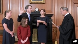 美国最高法院首席大法官约翰·罗伯茨在最高法院带领卡瓦诺宣誓就任大法官。阿什利·卡瓦诺捧着圣经，他们的女儿在场。