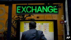 Seorang warga memeriksa nilai tukar di sebuah tempat penukaran uang di Buenos Aires, Argentina, pada 14 Juli 2022. (Foto: AP/Natacha Pisarenko)