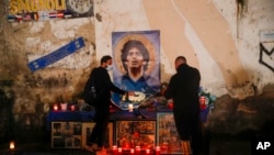 Orang-orang berkumpul dan menyalakan lilin untuk menghormati legenda sepak bola Diego Maradona, di lingkungan populer "Quartieri Spagnoli", di Naples, Kamis, 26 November 2020. (Foto: AP)