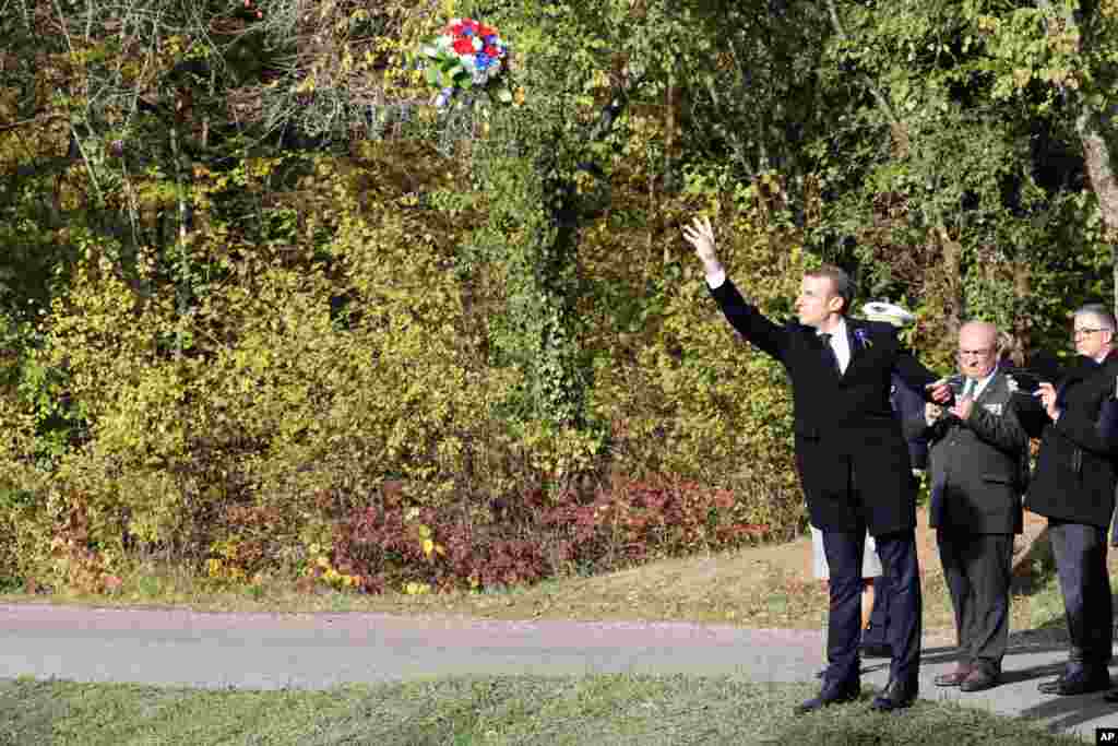 French President Emmanuel Macron throws a wreath of flowers at Les Entonnoirs, a site of the mines war, in Les Eparges, France, as part of the ceremonies marking the centenary of the end of World War I.