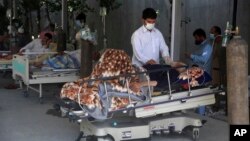 A man helps his father to drink juice at the Afghan-Japan Communicable Disease Hospital, for COVID-19 patients, in Kabul, Afghanistan, Thursday June 18, 2020. (AP Photo/Rahmat Gul)