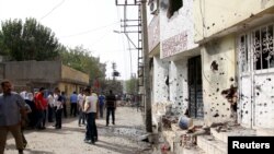 Penduduk kota berdiri di depan gedung yang rusak di kota Cizre, provinsi Sirnak, Turki, 12 September 2015.