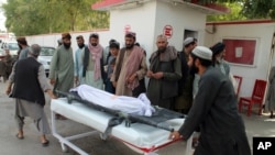Afghans carry the body of a man who was killed during an attack, in the southern Helmand province, June 29, 2020. 