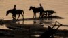 In this photo taken, Saturday, April 3, 2010, Cambodian men take their horses for washing in the Mekong river bank near Khporp village, Kandal province about 22 kilometers (14 miles) north of Phnom Penh, Cambodia.