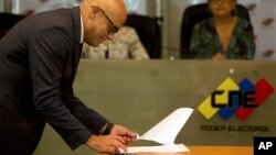 Communications Minister Jorge Rodriguez signs an agreement made with several opposition parties to delay presidential elections at the Venezuelan National Electoral Council in Caracas, Venezuela, March 1, 2018. 