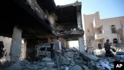 People inspect the wreckage of buildings that were damaged by Saudi-led coalition airstrikes, in Sanaa, Yemen, Tuesday, Jan. 18, 2022.