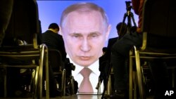 Journalists watch as Russian President Vladimir Putin gives his annual state of the nation address in Manezh in Moscow, Russia, Thursday, March 1, 2018. (AP Photo/Alexander Zemlianichenko)