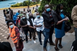 FILE - People wait to register for the first injection of the Oxford/AstraZeneca COVID-19 vaccine during the launch of a vaccination campaign, at the Kenyatta International Convention Centre in Nairobi, Kenya, April 21, 2021.
