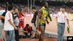 Jamaica's Usain Bolt walks away after being hit by a videographer on a Segway as Bolt celebrated winning the men’s 200m final at the World Athletics Championships at the Bird's Nest stadium in Beijing, Aug. 27, 2015.