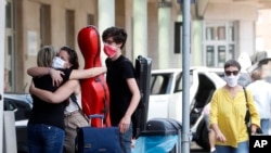 As Italy opened its border, Giuseppina Niglio, from Salerno, southern Italy, hugs her children Roberta and Alessandro, students at the Lugano School of music Conservatory in Switzerland, at the Italian-Swiss border, June 3, 2020. 