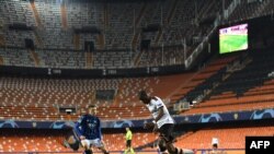 FILE - This handout photograph released by UEFA March 10, 2020, shows Valencia CF and Atalanta players competing for the ball in a stadium without spectators due to coronacirus fears, at Estadio Mestalla, in Valencia, Spain. 