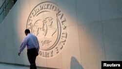 Seorang pria berjalan melewati logo Dana Moneter Internasional (IMF) di kantor pusatnya di Washington, AS, 10 Mei 2018. (Foto: REUTERS/Yuri Gripas)