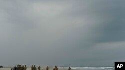 Security forces form a cordon around the body of Emmanuel Cheo Ngu, of Cameroon, on Boca Barra Beach, in Puerto Arista, Mexico, Oct. 11, 2019. The 39-year-old man was traveling with a group of people in a small boat when it overturned.