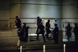 FILE - Police officers remove fencing put up around a government building during a rally in Portland, Oregon, July 17, 2020.