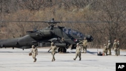 ​ທະ​ຫານ ສະ​ຫະ​ລັດ ກຽມ​ພ້ອມ​ເພື່ອ​ທຳ​ການ​ຊ້ອມ​ຍິງ​ລູກ​ປືນ​ແທ້​ໃກ້​ກັບ​ເຮືອ​ບິນ ເຮ​ລິ​ຄັອບ​ເຕີ ອາ​ປາ​ເຊ ໃນ​ລະ​ຫວ່າງ​ການ​ຊ້ອມ​ລົບ​ກັບ ເກົາຫຼີ​ໃຕ້, ເມືອງ ໂປ​ຊອນ, ເກົາຫຼີ​ໃຕ້, 14 ພະ​ຈິກ, 2023.(AP Photo/Lee Jin-man)