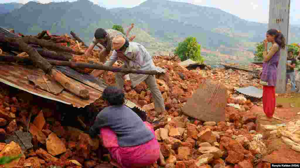Residents of a destroyed home in Ratomatey scavenge for corn in the rubble.