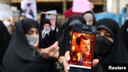 Seorang pengunjuk rasa menunjukkan kartun Presiden Prancis Emmanuel Macron di ponselnya saat protes mengutuk majalah Prancis Charlie Hebdo yang menerbitkan kartun yang menghina pemimpin Iran Ayatollah Ali Khamenei, di Teheran, Iran, 11 Januari 2023 (Foto: WANA via Reuters)