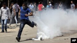 An Egyptian protester runs away from a tear gas canister fired by riot police, near street leading to US embassy during clashes in Cairo, Egypt, Sept 14, 2012.