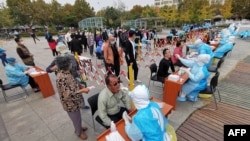 Health workers take swabs from residents to be tested for the COVID-19 coronavirus as part of a mass testing program following a new outbreak of the coronavirus in Qingdao, in China's eastern Shandong province on October 13, 2020. (Photo by STR / AFP) / C