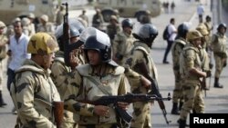Army soldiers take positions as Al-Azhar University student members of the Muslim Brotherhood and supporters of ousted Egyptian President Mohammed Morsi, shout slogans against the military and Interior Ministry during a march towards the Rabaa al-Adawiya square in Cairo, Oct.28, 2013.