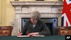 Britain's Prime Minister Theresa May signs the official letter to European Council President Donald Tusk, in 10 Downing Street, London, Tuesday March 28, 2017, invoking Article 50 of the bloc's key treaty.