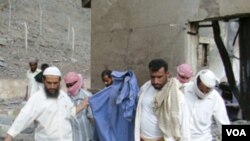 Warga setempat membawa anggota tubuh seorang korban tewas yang ditemukan di dalam pabrik amunisi di Jaar, Senin (28/3).