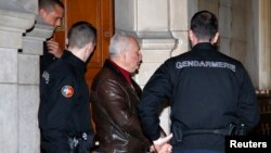 FILE - Ilich Ramirez Sanchez, known as "Carlos the Jackal," is surrounded by French gendarmes as he leaves the Paris courthouse, March 3, 2014. 