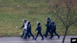 图为在星期天的抗议中，白俄罗斯防暴警察逮捕了一名示威者。