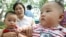 FILE - Two Chinese babies sit with their mothers in a Beijing park, July 10, 2003. 