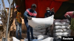 FILE - Workers carry the aid provided by the World Food Program (WFP) for distribution in Pissila, Burkina Faso, Jan. 24, 2020. 
