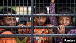 ពលករ​ខ្មែរ​និង​​ក្រុមគ្រួសារ​មើល​ចេញ​ក្រៅ​ពី​រថយន្ត​​ទ្រង់​ខណៈ​ដែល​ពួក​គេ​រង់​ចាំ​ឆ្លង​កាត់​ព្រំដែន​ថៃ-កម្ពុជា​នៅ​ត្រង់​អារញ្ញប្រទេស (Aranyaprathet) ខេត្ត​ស្រះកែវ (Sa Kaew) កាល​ពី​​ថ្ងៃ​ទី​១៥ ខែ​មិថុនា ឆ្នាំ​២០១៤។